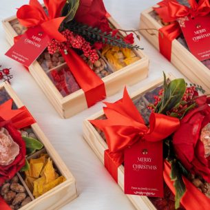 Luxury 9-compartment wooden Christmas snack box with red ribbon, premium nuts, dried fruit and chocolates by Graze & Bliss.